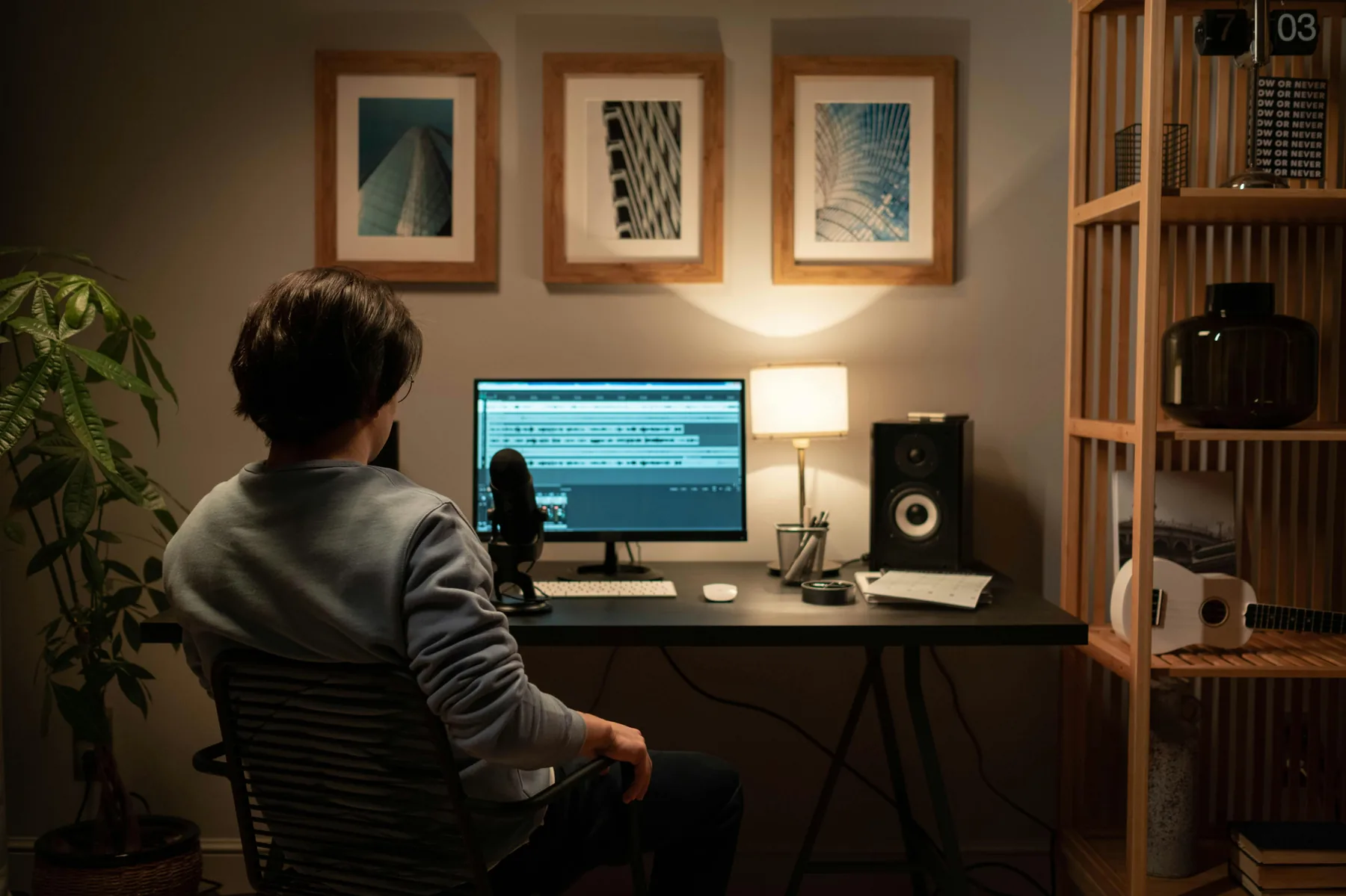 Editor mixing audio waveforms on screen with studio monitor speaker